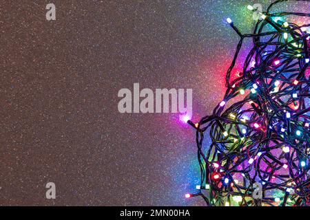 Una ghirlanda di lampadine multicolore su uno sfondo argento con scintille. Disposizione piatta, vista dall'alto, spazio di copia Foto Stock