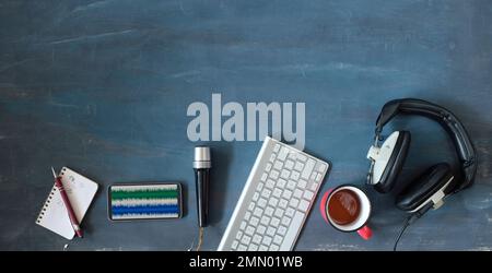 Concetto di musica o podcast con cuffie eleganti, microfono vintage, caffè e tastiera del computer su tavolo blu, vista dall'alto, piatto con spazio copia. Foto Stock