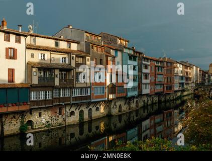 Francia, Tarn, Castres, case sul Agoût, vista di edifici lungo le rive del fiume sotto un cielo tempestoso