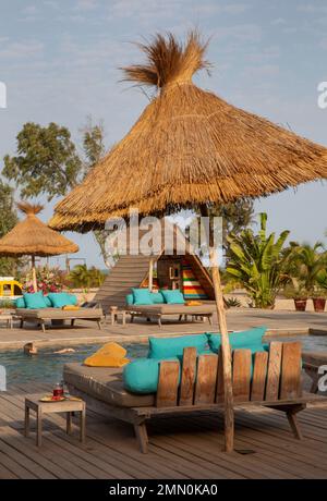 Senegal, il delta di Saloum dichiarato patrimonio mondiale dall'UNESCO, Palmarin, Yokan Lodge, donna che nuota nella piscina decorata con sdraio in legno, ombrelloni di palma e vegetazione tropicale Foto Stock