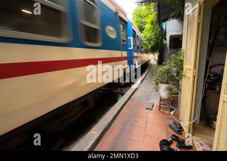 Hanoi, Vietnam, gennaio 2023. il passaggio di un treno lungo i binari tra le case del centro storico Foto Stock