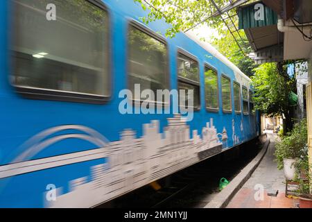 Hanoi, Vietnam, gennaio 2023. il passaggio di un treno lungo i binari tra le case del centro storico Foto Stock