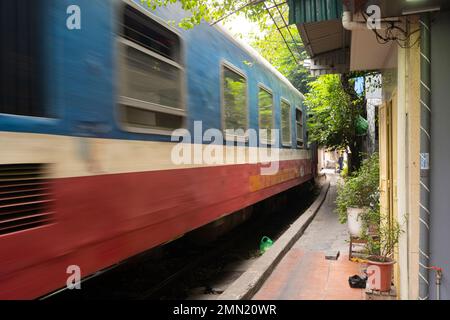 Hanoi, Vietnam, gennaio 2023. il passaggio di un treno lungo i binari tra le case del centro storico Foto Stock