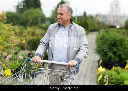 Uomo che sceglie giovani pianta nel mercato Foto Stock