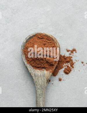 Cucchiaio di cacao in polvere su fondo grigio. Vista dall'alto. Foto Stock