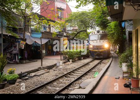 Hanoi, Vietnam, gennaio 2023. il passaggio di un treno lungo i binari tra le case del centro storico Foto Stock