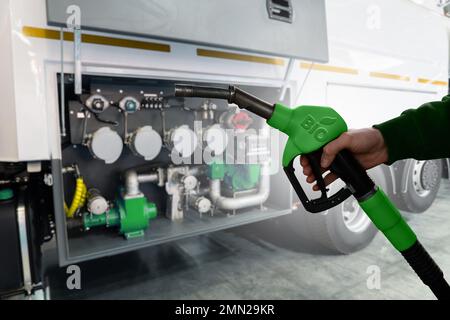 Mano con ugello del carburante con iscrizione BIO. Concetto di decarbonizzazione del carburante biologico a emissioni di carbonio neutre Foto Stock