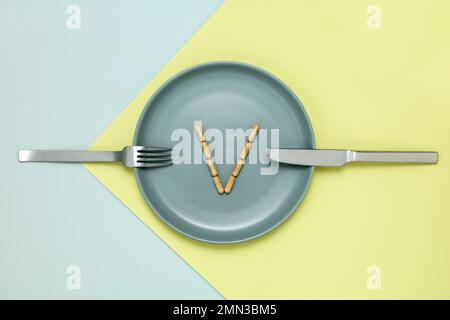 Le capsule di vitamina si dispongono in una v su piatto blu verde della cena Foto Stock