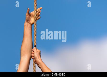 Donna atletica che si allena e si arrampica su una corda, durante il corso di ostacolo nel campo di stivali Foto Stock