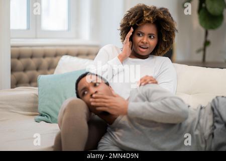 Coppia nera scioccata che guarda l'orrore a casa Foto Stock