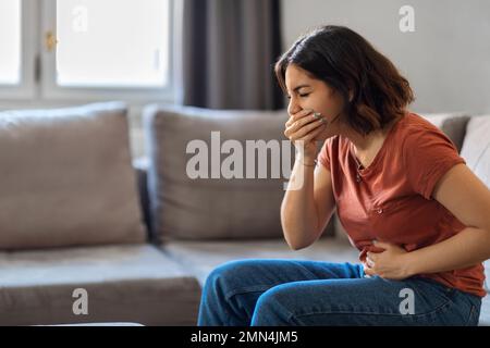 Ritratto della giovane donna araba che soffre di nausea a casa Foto Stock