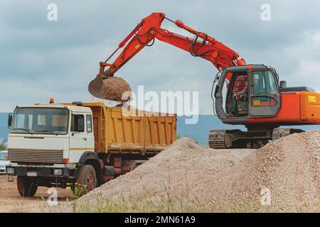 L'escavatore carica una roccia dell'autocarro nella cava Foto Stock