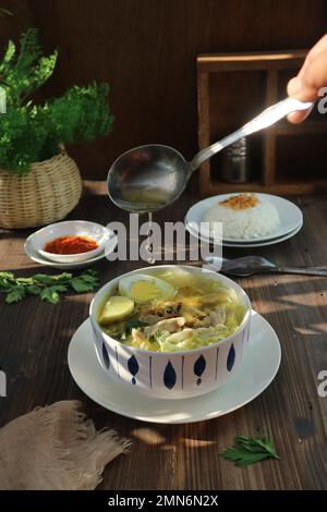 Versare la zuppa di pollo con un cucchiaio Foto Stock