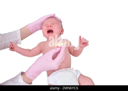 Il medico dà un succhietto a un neonato, isolato su uno sfondo bianco. L'infermiera in uniforme lenisce un bambino che piange. Bambino di due mesi Foto Stock