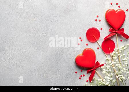 struttura in biscotti rossi a forma di cuore, lecca, dolci e fiori Foto Stock