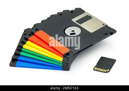 Pila di dischetti a dischetti colorati e scheda di memoria sd isolata su sfondo bianco. Dispositivi di storage nuovi e legacy. Foto Stock