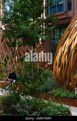 Qualcuno seduto sulla panca che corre lungo i padiglioni. Osnaburgh Pavilion a Regents Place, Londra, Regno Unito. Architetto: NEX, 2022. Foto Stock