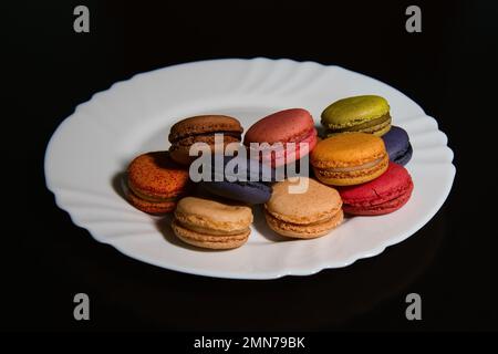 Macaron su un piatto su sfondo nero Foto Stock