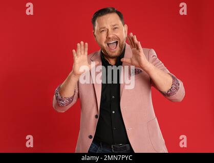 Ritratto di urlando uomo maturo su sfondo rosso Foto Stock