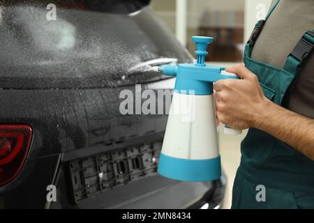 L'operatore spruzzerà acqua sul finestrino dell'auto prima di colorare in officina, in primo piano Foto Stock