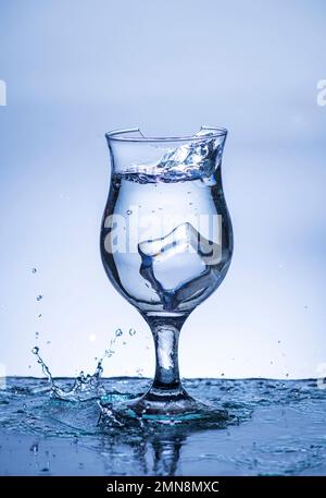 L'immagine di versare acqua potabile, in un vetro rotto, che fa sentire rinfrescato su sfondo bianco sfocato, spruzzi d'acqua, acqua frizzante, Foto Stock