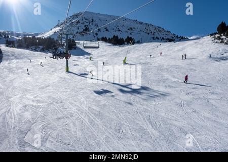 Pista da sci con sciatori che scivolano lungo la pista nei Pirenei, Andorra, foto con copyspace. Foto Stock