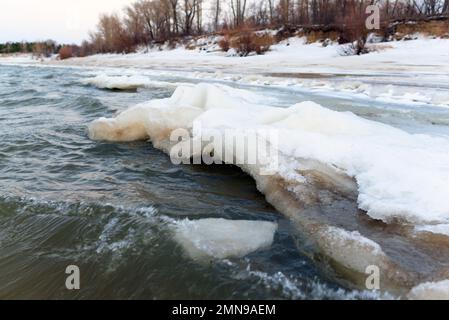 Il primo ghiaccio debole sale in onde dal flusso d'acqua. Foto Stock