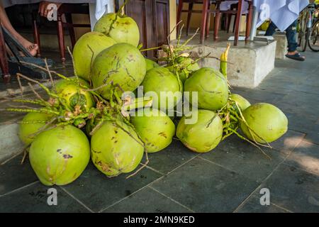 Mucchio di noci di cocco fresche giacendo sul terreno ad un mercato. Foto Stock