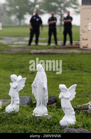 In this Wednesday, May 23, 2018 photo, corrections officers stand behind small figurines near the dock on Hart Island in New York. Officials let reporters get a rare look this week at Hart Island, the place that has served as New York City’s potter’s field for 150 years. (AP Photo/Seth Wenig)