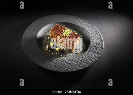 Torta al cioccolato con noci e pistacchio isolato su fondo nero. Pasticceria da panetteria fatta in casa Foto Stock