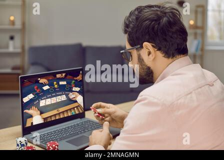 Il giovane uomo d'azzardo partecipa al torneo di poker online mentre si rilassa a casa. Foto Stock