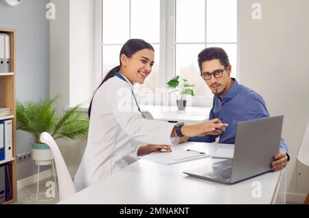 Medico di sesso femminile che mostra i risultati dei test al paziente sul computer portatile Foto Stock