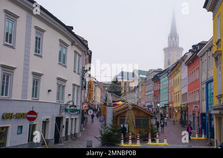 Villach, Austria - Dicembre 24 2022. Bancarelle del mercato di Natale in via Hauptplatz su una lieve nebbia della vigilia di Natale nel centro storico di Villach Foto Stock