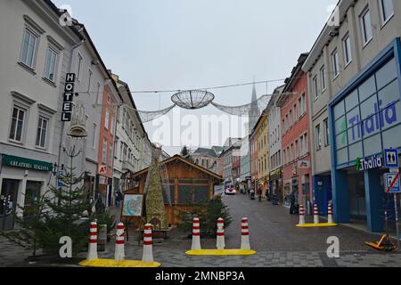 Villach, Austria - Dicembre 24 2022. Bancarelle del mercato di Natale in via Hauptplatz su una lieve nebbia della vigilia di Natale nel centro storico di Villach Foto Stock