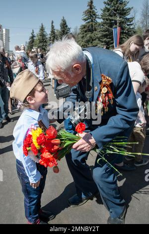 KOLOMNA, regione di Mosca, Russia 9 maggio 2015. Un ragazzino si congratula con un veterano. Reggimento immortale, giorno della vittoria sulla Germania nazista. Foto Stock