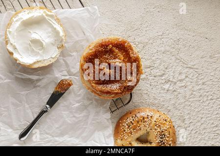 Bagel appena sfornati con formaggio cremoso e marmellata di fichi su carta da forno Foto Stock