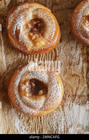 Dolci appena sfornati con marmellata su carta da forno decorata con zucchero in polvere Foto Stock