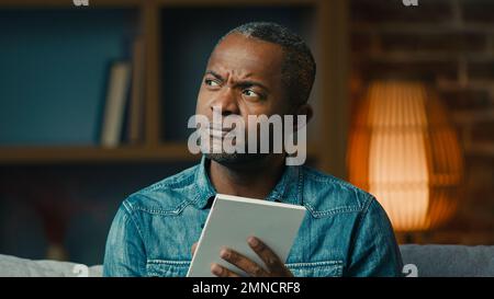 Uomo afroamericano adulto pensivo indoor pensare in profondità nei pensieri creare strategia uomo d'affari premuroso prendere appunti nella pianificazione del notebook Foto Stock