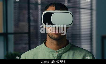 Spaventato uomo afroamericano preoccupato indossando occhiali di realtà virtuale giocare spaventoso gioco 3D in mondo metaverse digitale indoor sentire paura orrore paura paura Foto Stock