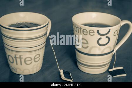 Due tazze di caffè con testo colorato riempito di tè su un tavolo di legno. Foto Stock