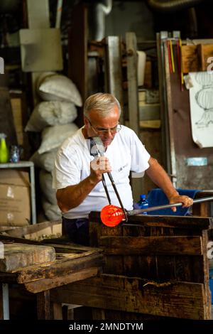 Un abile artigiano al lavoro in una bottega di vetro a Murano, Venezia Foto Stock