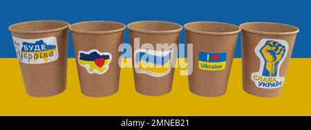 Cinque tazzine monouso di carta di caffè con adesivi patriottici. Traduzione del testo sugli adesivi "tutto sarà Ucraina", "Gloria all'Ucraina" Foto Stock