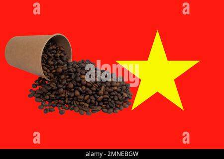 Una tazza di carta monouso capovolta riempita con chicchi di caffè tostati sullo sfondo della bandiera del Vietnam (primo piano) Foto Stock