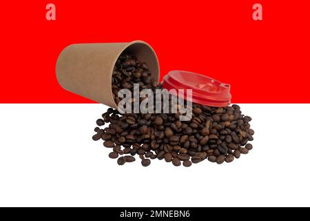 Una tazza di carta monouso capovolta con un coperchio riempito di chicchi di caffè tostati sullo sfondo della bandiera indonesiana (primo piano) Foto Stock