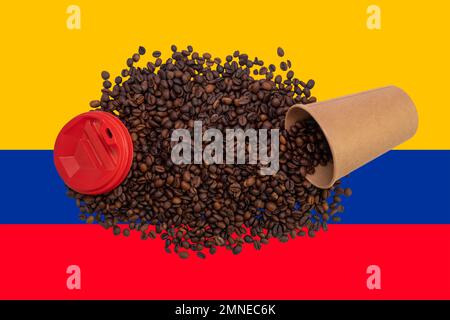 Una tazza di carta usa e getta rovesciata con un coperchio pieno di chicchi di caffè arrostiti sullo sfondo della bandiera colombiana (primo piano) Foto Stock