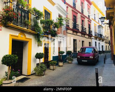 Autobus VW rosso sulla strada stretta tra case tipiche della città vecchia, Siviglia, Andalusia, Spagna Foto Stock