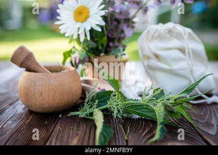 ortica comune, ortica bruciata, erbe medicinali vicino al mortaio. Sacchetto con erbe essiccate. Messa a fuoco morbida. Foto Stock