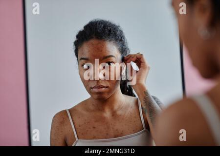 Ritratto di giovane donna nera con cicatrici acne guardando in specchio insicuro in apparenza Foto Stock