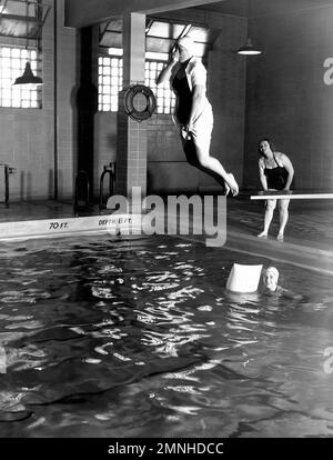 Naval Hospital St. Albans, Long Island, New York. La piscina e' usata per scopi di ricreazione e addestramento. Qui, un Indoctrinee del corpo infermieristico apprende un'immersione salvavita dalla nave dall'istruttore di nuoto della Croce Rossa in una lezione pomeridiana di ca. 1958 Foto Stock