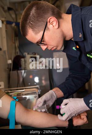 Un Corpsman 2nd Classe, assegnato alla Fleet Surgical Team (FST) 4, prende il sangue da un paziente nel reparto medico della nave (USS Bataan) ca. 2020 Foto Stock